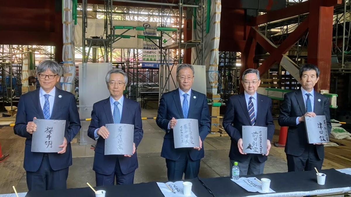 記名した瓦を手にする藤井輝夫総長（中央）、前田家当主の前田利宜さん（右から2人目）ら