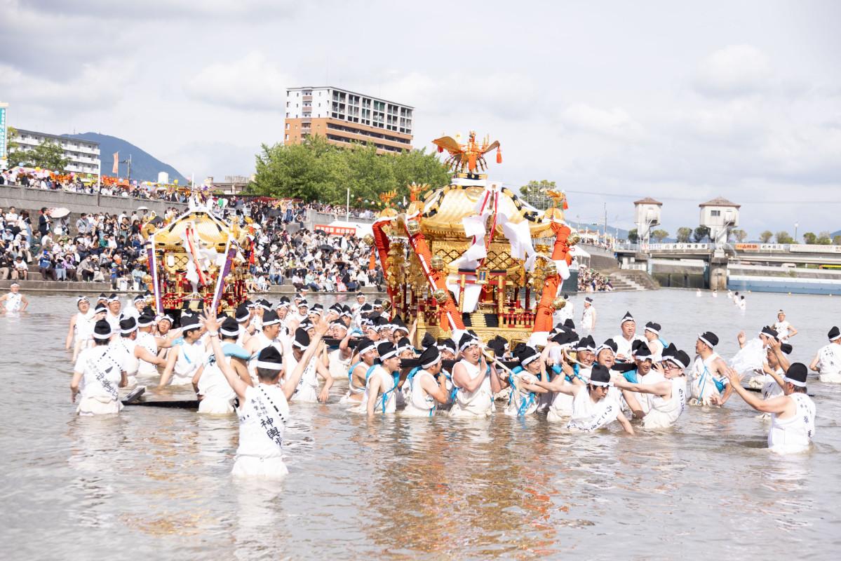 川を渡る白鳥神社のみこし（左）と風治八幡宮のみこし＝田川・川渡り神幸祭（写真提供＝田川市）