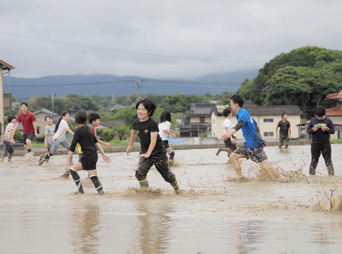 鬼ごっこで田んぼを駆け回る児童ら（写真提供＝猪位金学園）