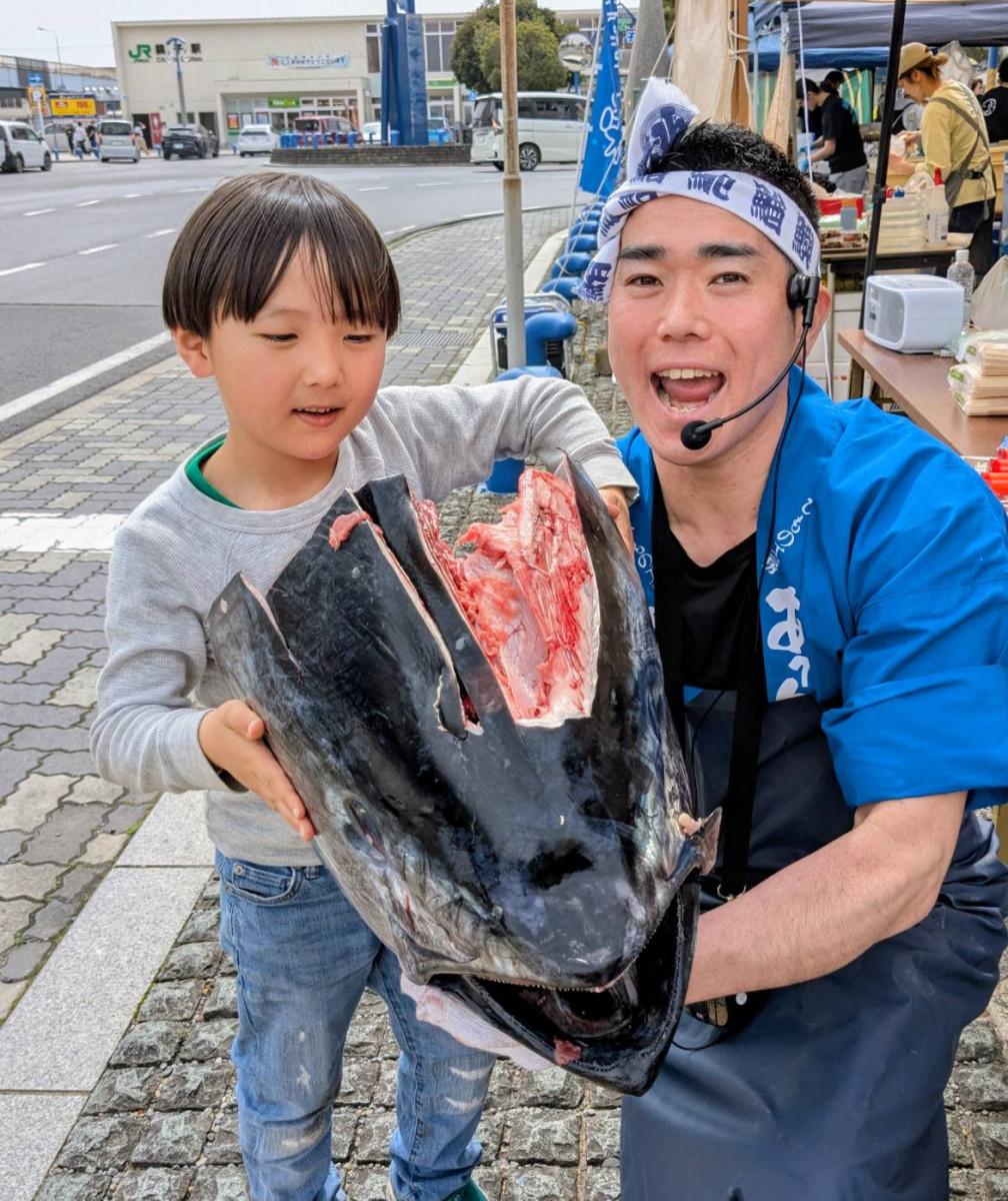 「マグロの解体ショー」で大きなマグロの頭を持ち上げる子どもとスタッフ