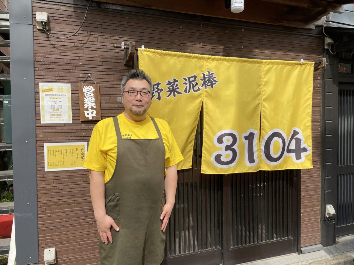 店主の辻さん。のれんとTシャツはカレーを意識して黄色にしている