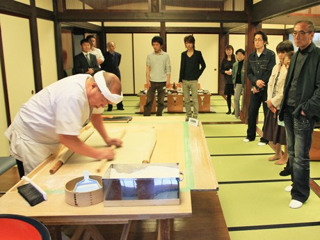 そば打ちを披露する高橋名人の技に見入る参加者