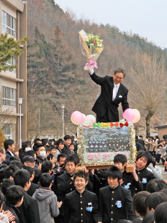 卒業5期生の恩師･松井健治さんを担ぐ生徒たち