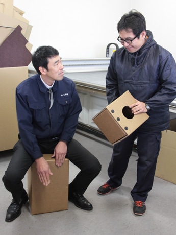 段ボールカホンを実演してみせる下畑社長(左)と社員
