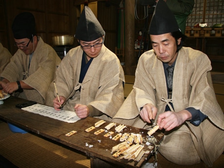 麻ガラを小刀で割りご神託を調べる氏子若連中たち