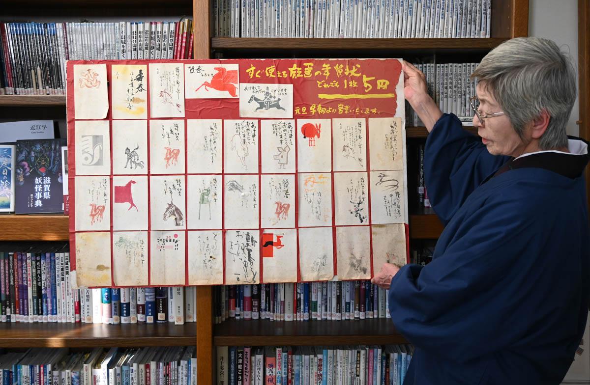 年賀状の見本帖を手にするサンライズ出版の岩根順子社長