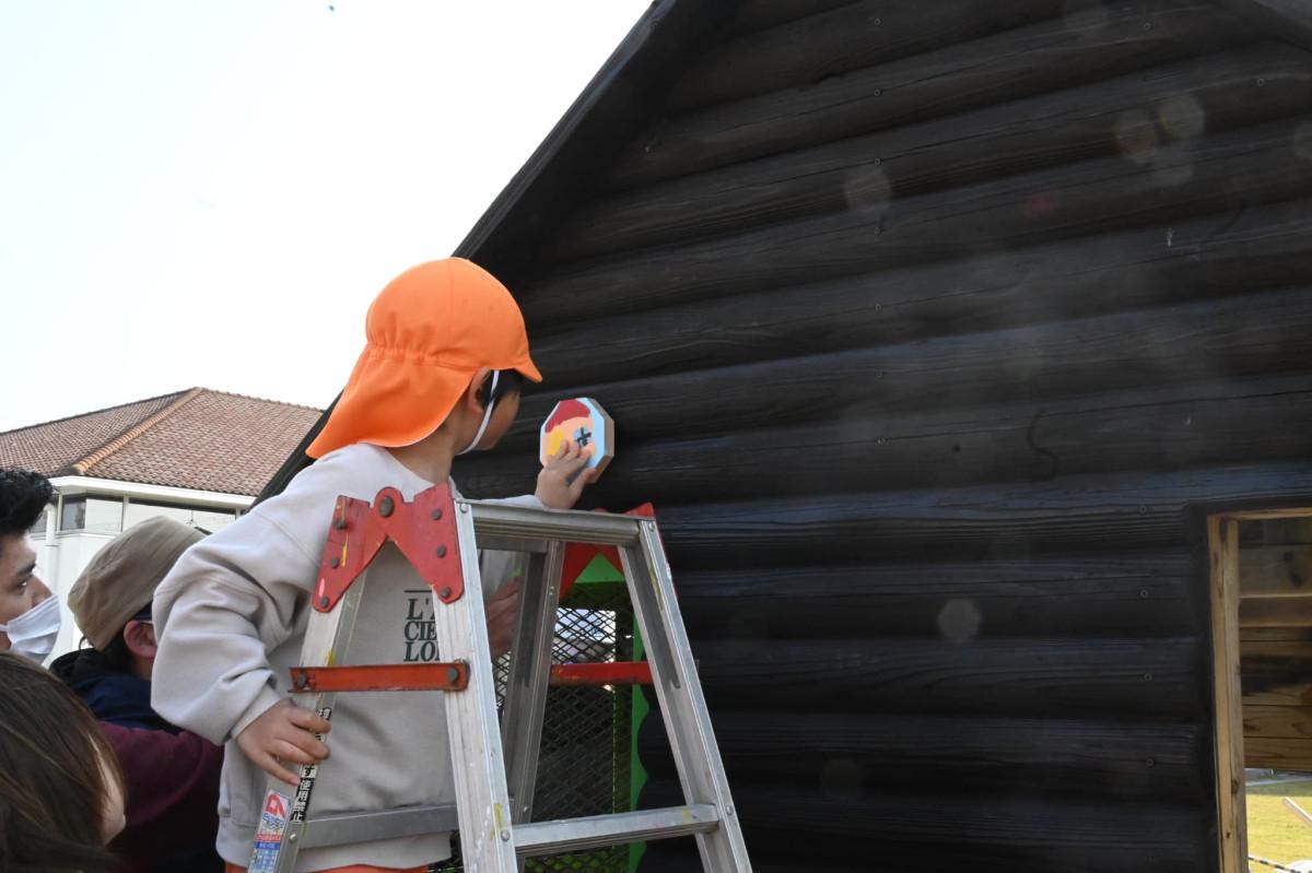 絵や模様を描いた木材を、企業担当者らと一緒にハウスの外壁へ貼り付ける作業に取り組んだ