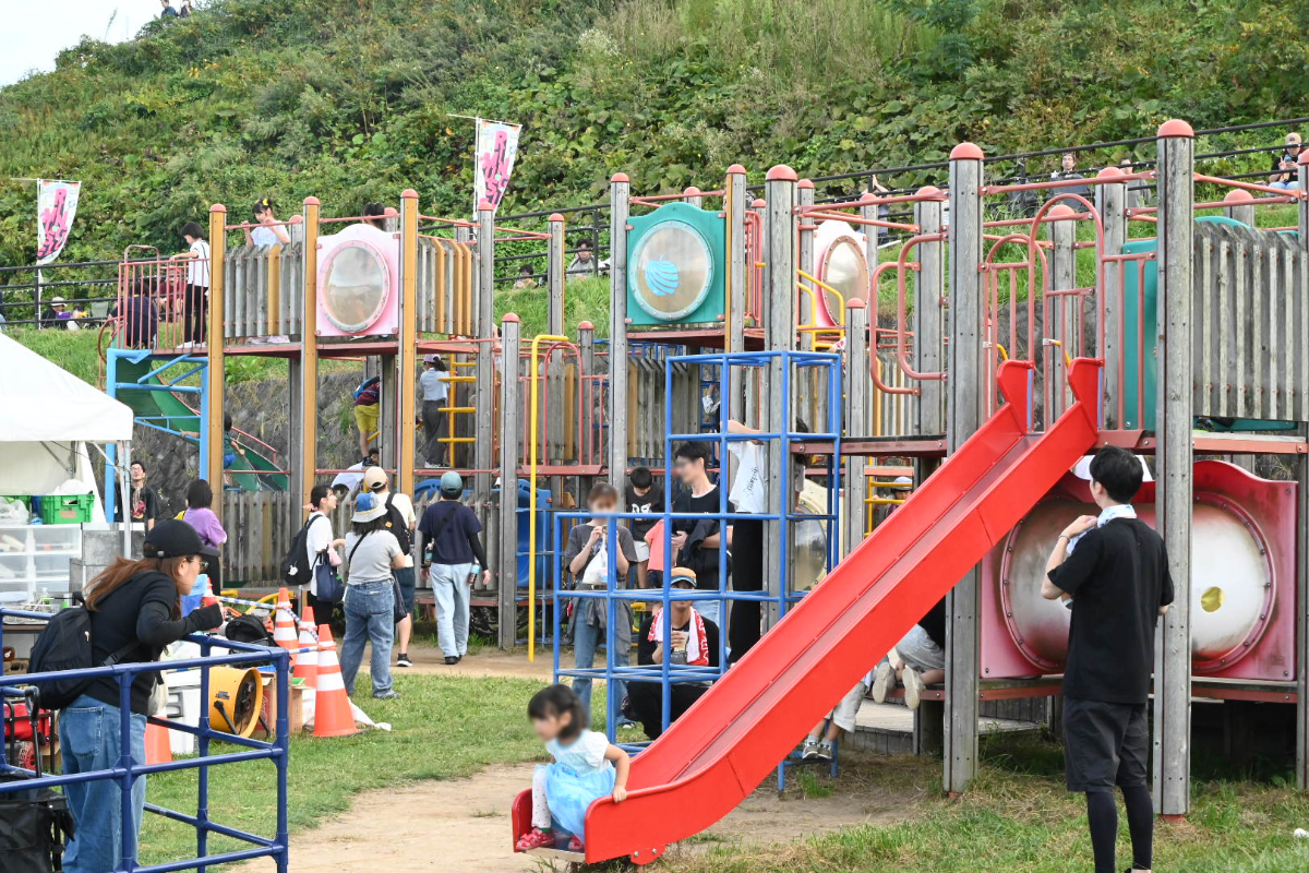 遊具で遊ぶ子どもたちと見守る親