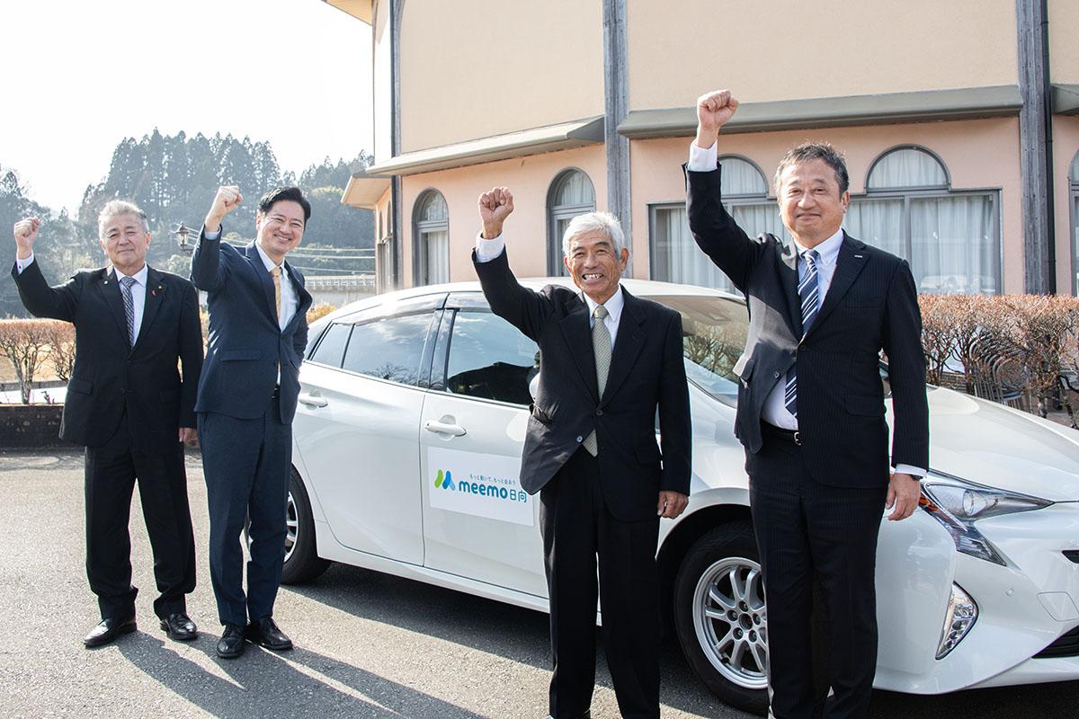 「ミーモ日向」第1号ドライバーとなった東郷まちづくり協議会会長の鈴野浅夫さん（右から2人目）。西村賢日向市長（左から2人目）らと