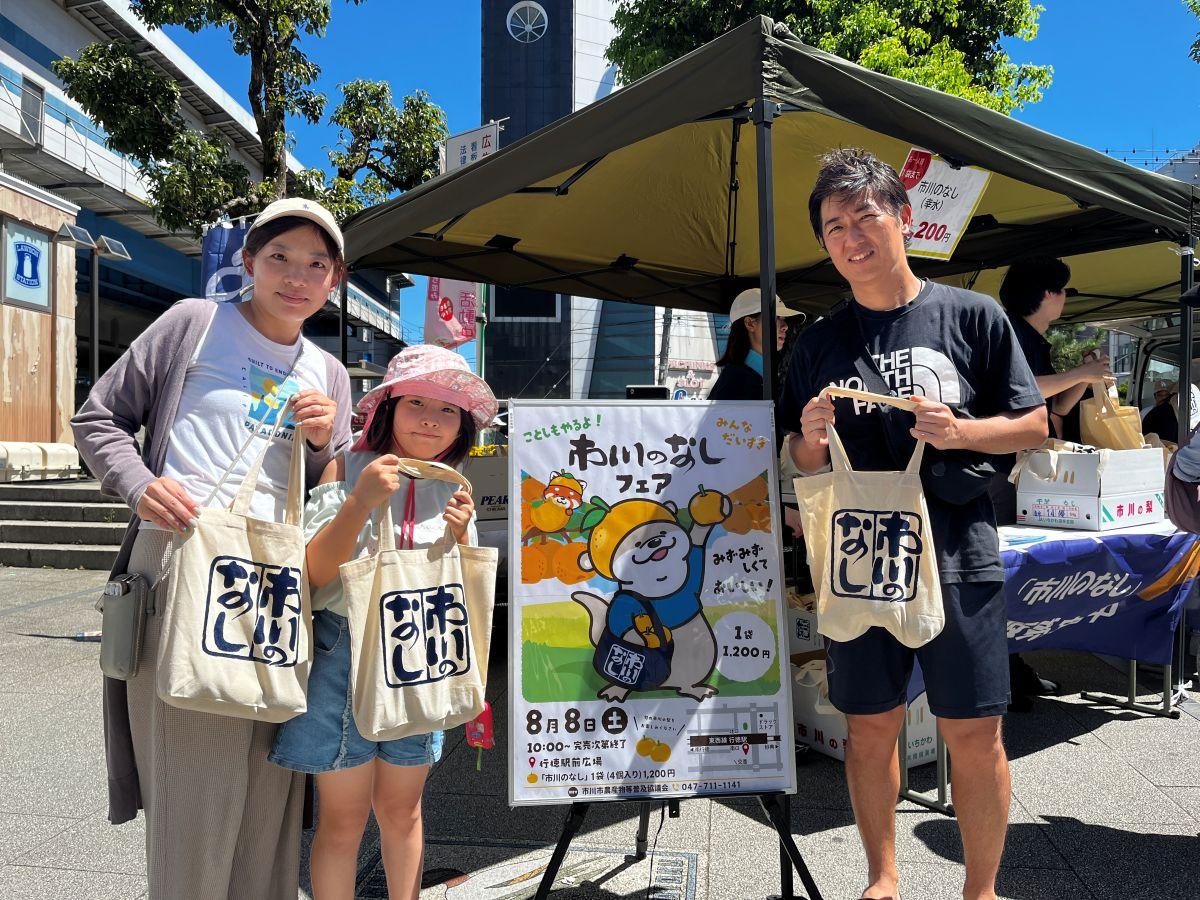 「市川のなしオリジナルバッグ」に入ったナシを購入した家族連れ