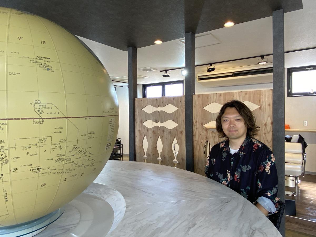 卑弥呼グループ統括の松下勇樹さんと地球儀のオブジェ