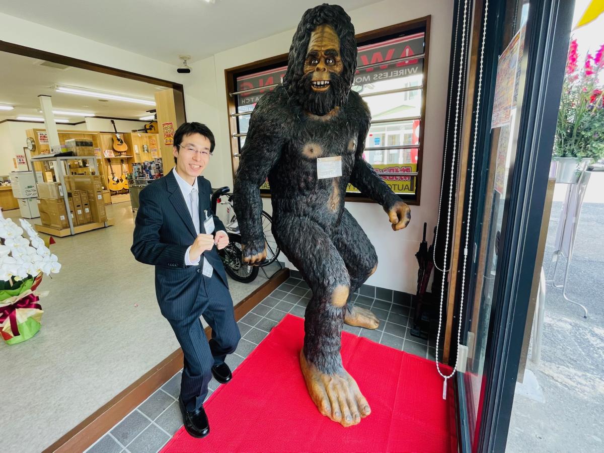 責任者の谷口勇吾さん、来店客を出迎えるキャラクターと同じポーズで「リユース」を呼び掛ける