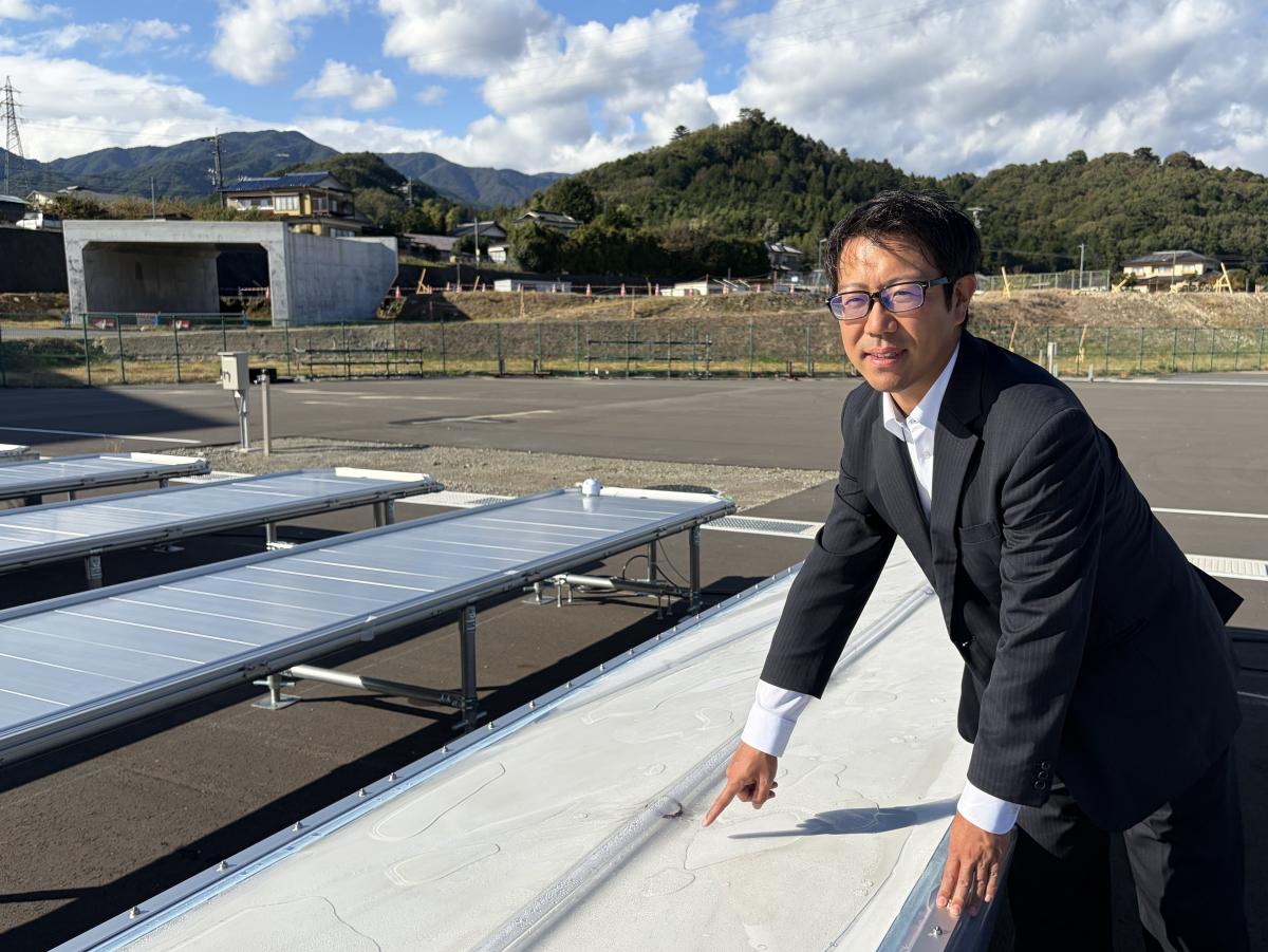 水素パネルを前に、信州大学学術研究・産学官連携推進機構の宮原大地准教授