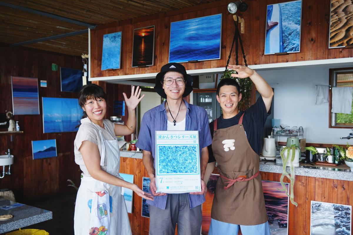 今治市大島・カレイ山山頂のカフェ「遠見茶屋 天（あま）」で7月11日、個展「波かんさつシリーズ展」が始まった。因島出身の若手写真家・上原和人さん（中央）と店主の青野右京さん（右）、店長を務める大原妃南乃さん（左）。
