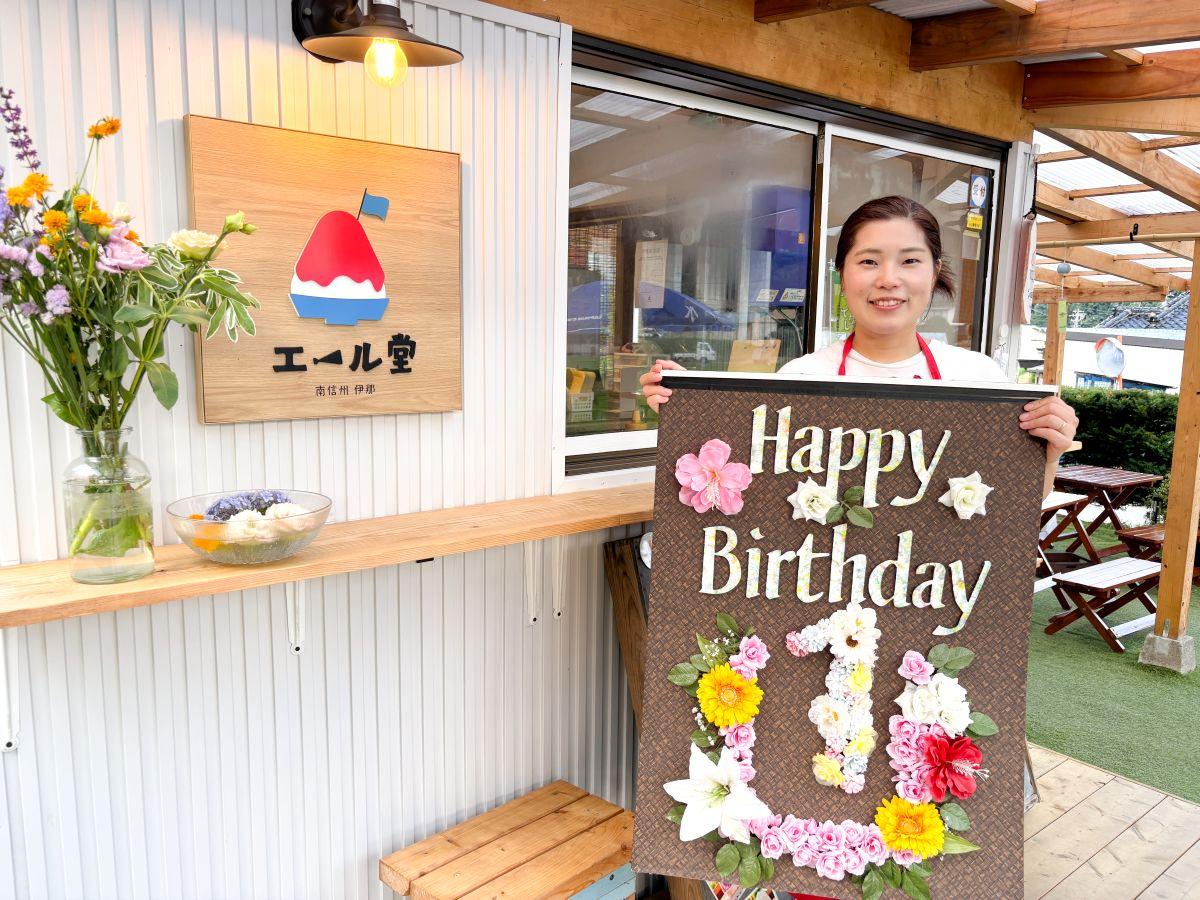 店主の山本さんが持つ1周年記念の看板は友人が作ってくれたもの