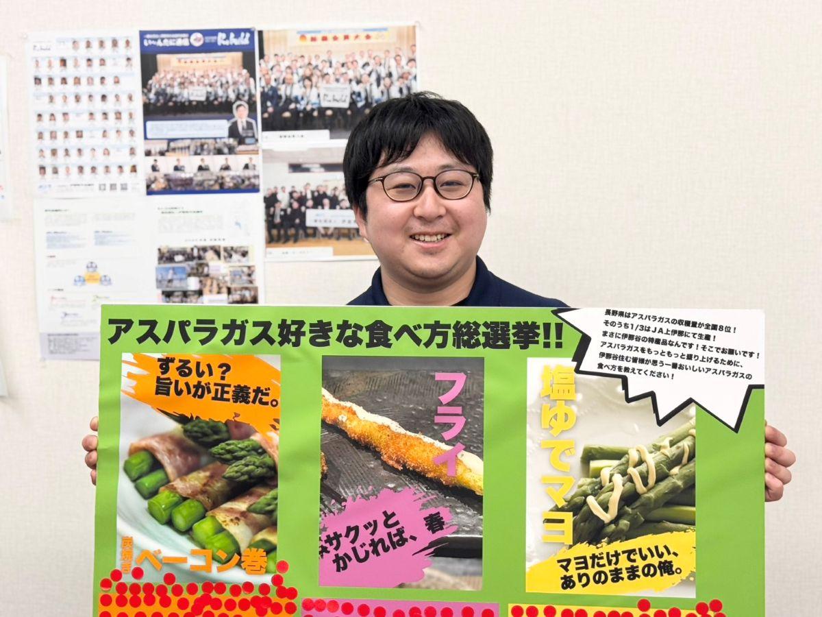 「アスパラガスの食べ方総選挙」のパネルを手にイベントをPRする伊那青年会議所地域共創委員会の桑澤優作さん