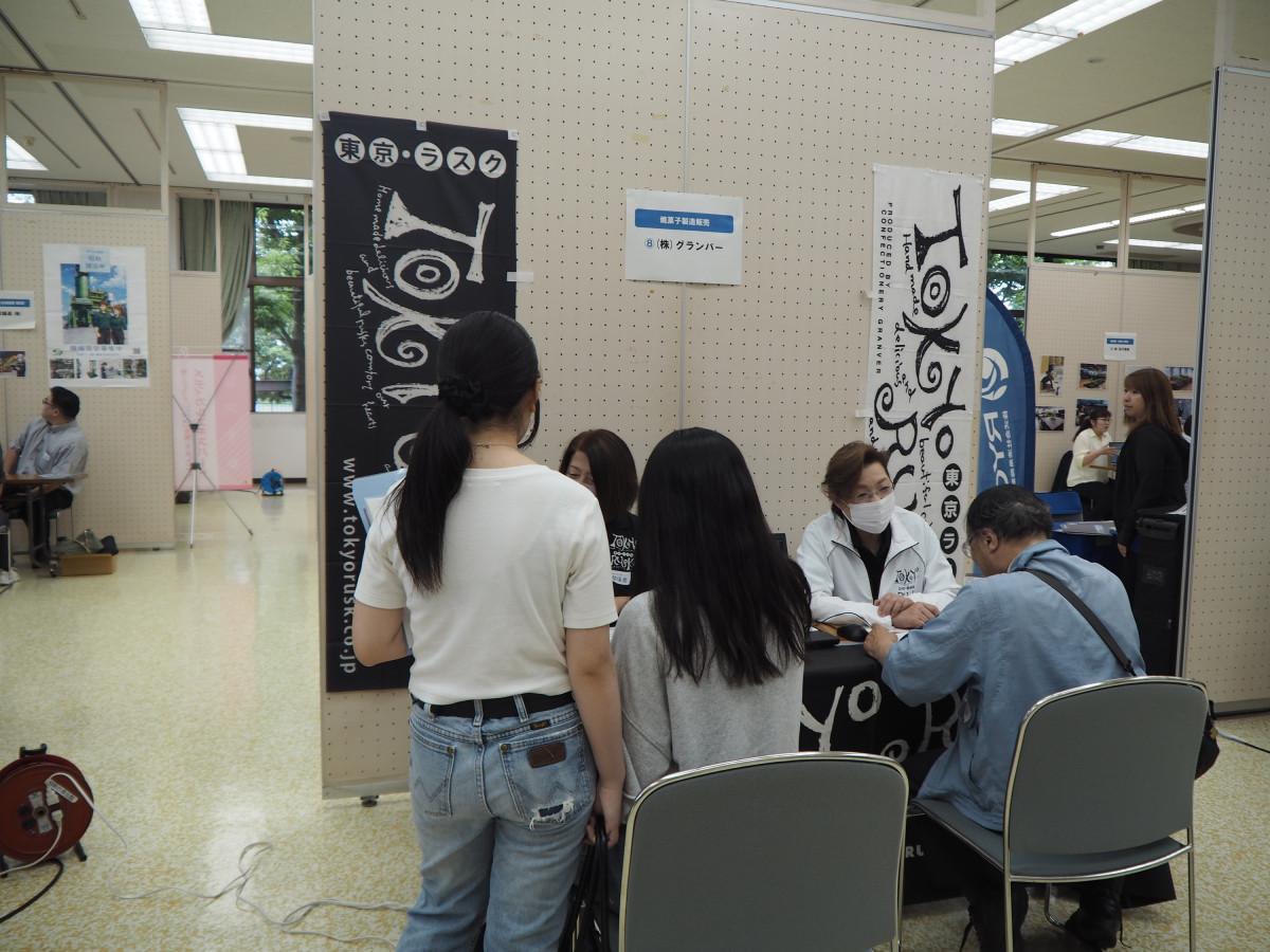 企業ブースで担当者の説明を聞く来場者