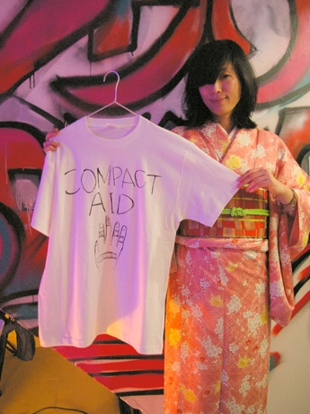 「COMPACT AID!」のためにデザインしたTシャツを掲げる工藤キキさん