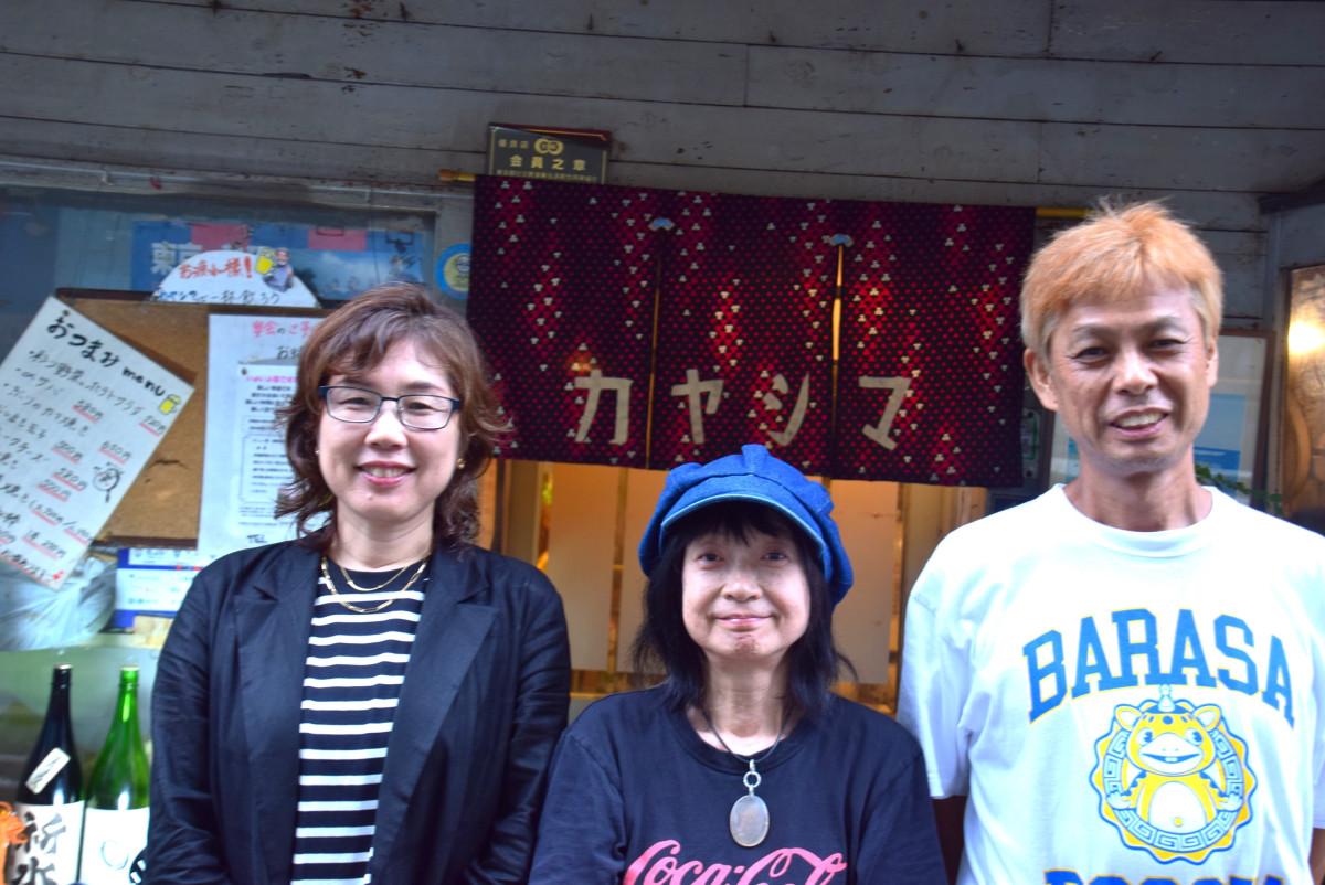 映画の舞台に使われた吉祥寺通り沿いで営業する「お酒と食事の店カヤシマ」の前で、脚本・音楽の諏訪霜月(平田暢子)さん(左)、監督のいなだゆかりさん(中央)、プロデュースの山田浩之さん(右)