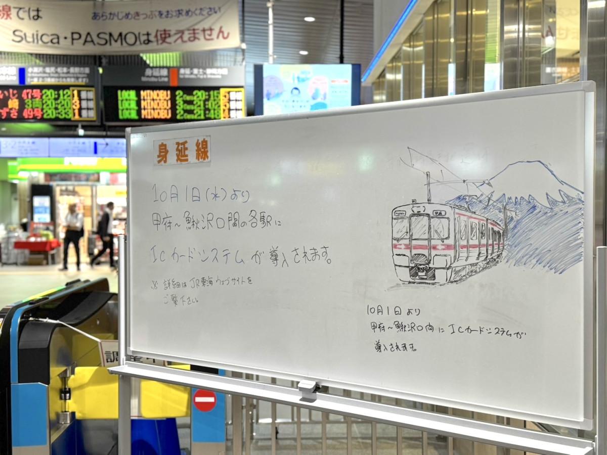 甲府駅の改札口に設置されたホワイトボードで案内する様子。