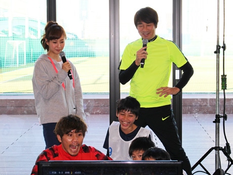 ウイトレを行う小学生と柏木陽介選手(手前左)。画面を見ながら解説する中西哲生さん(後列右)と藤本美貴さん(後列左)