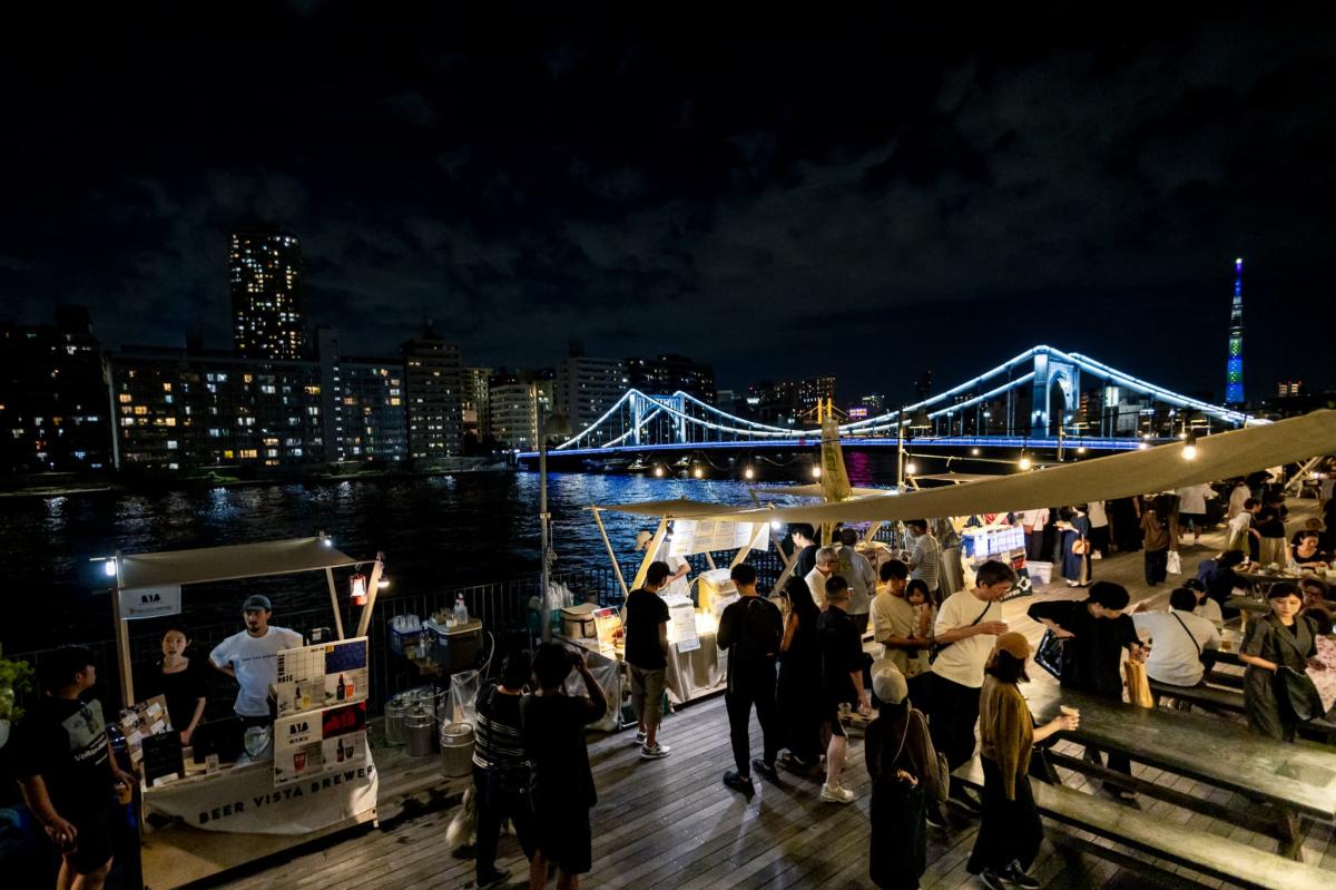 川沿いのデッキ「かわてらす」からの夜景を楽しみながらビールを味わう