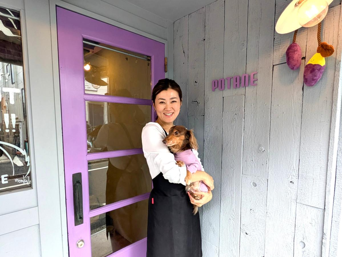 店頭に立つ店主の倉上さんと看板犬のピノ