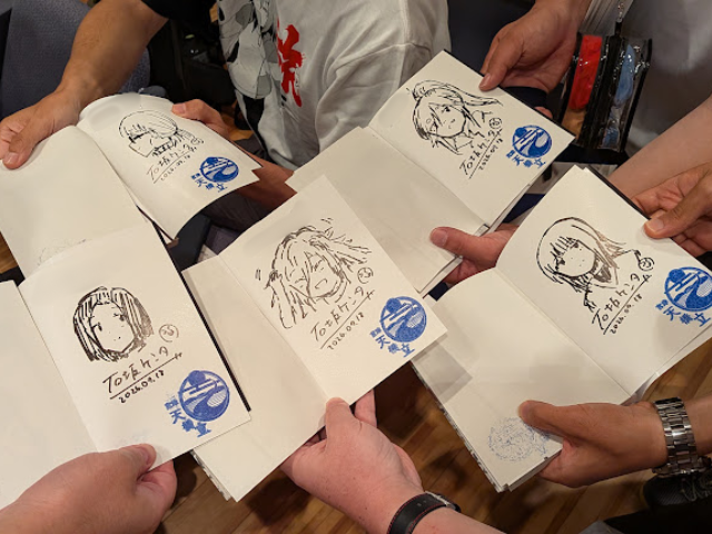 直筆イラスト入りサイン本を手にする参加者ら - 京丹後経済新聞