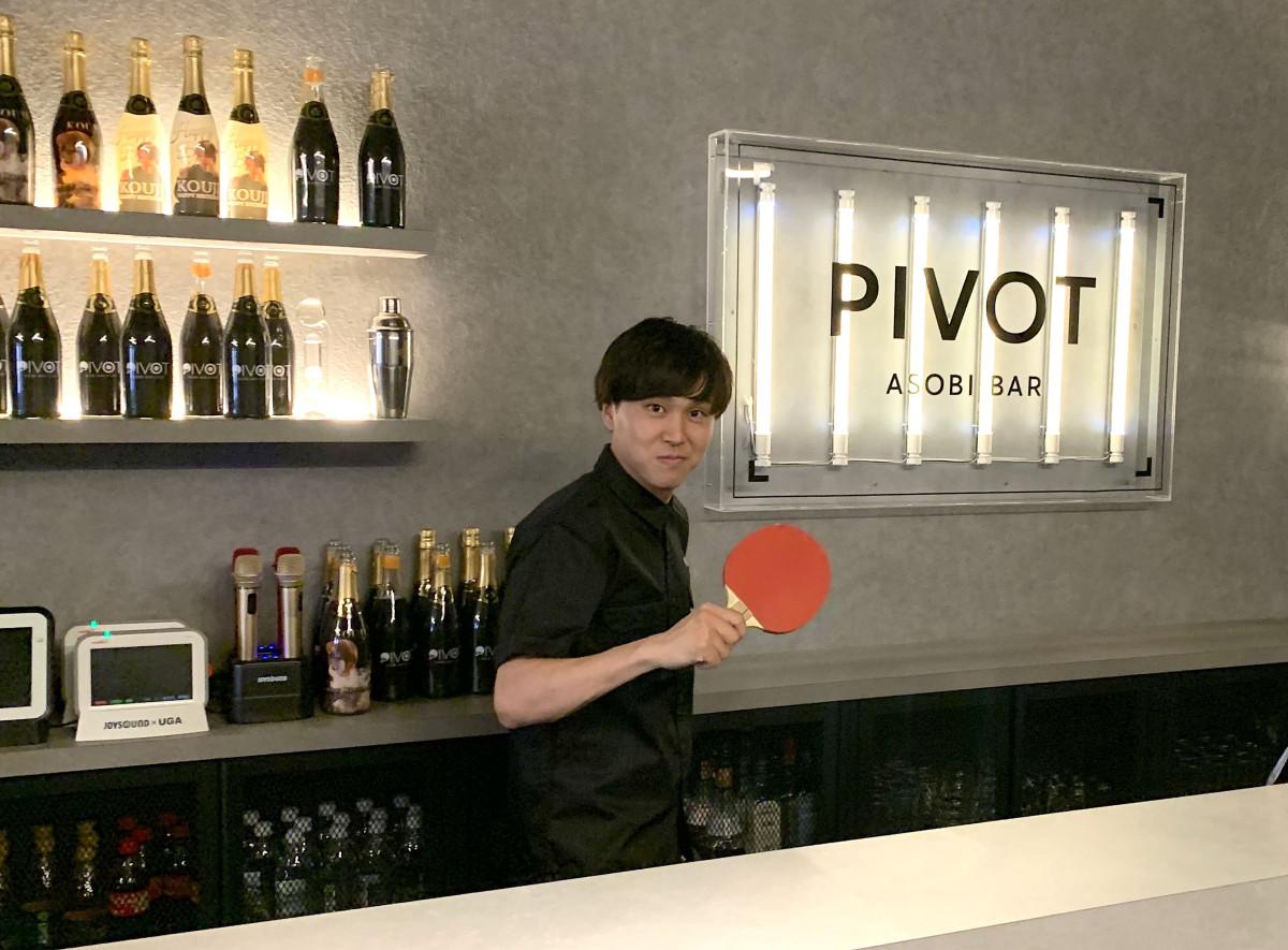カウンターで卓球のラケットを構える店主の河内さん