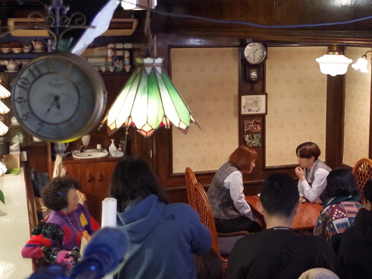 「ティーハウス リーベ」で行われた撮影。店主役の伊勢志摩さん（左）とOL役の忠犬立ハチ高の2人