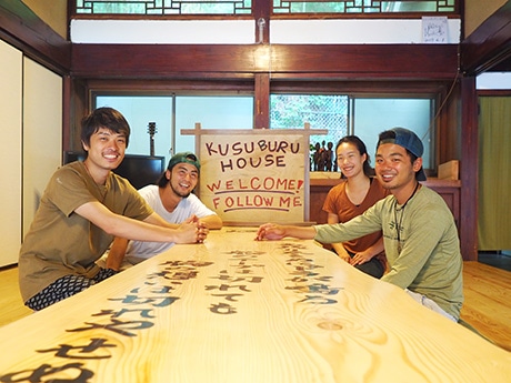ゲストハウス「KUSUBURU HOUSE」を運営する岩井明人さん(写真奥左)と柴田悠平さん(同手前右)、佐々木鈴夏さん(同奥右)、嶋田和史さん(同手前左)。同ゲストハウスの居間で撮影