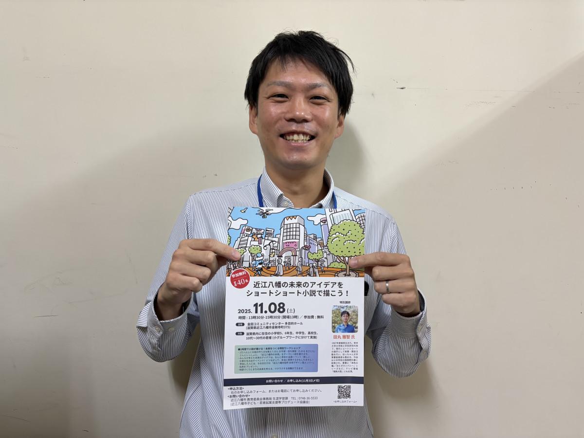 講座のチラシを笑顔で掲げる岡地さん