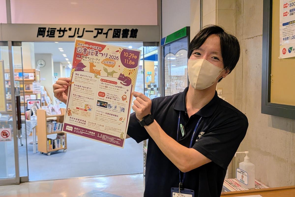 「図書館まつり2026」のチラシを手にする岡垣サンリーアイの職員