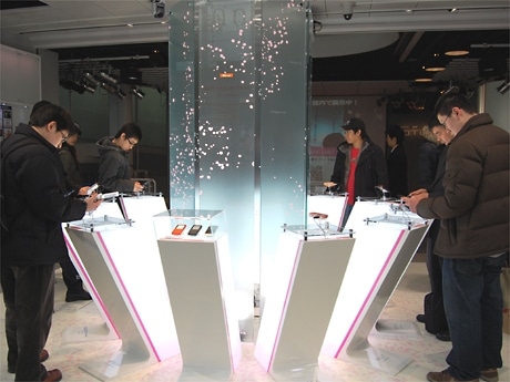 原宿で同17日に始まったau携帯電話「春モデル」の展示イベント（写真＝会場では新モデルに見入る男性の姿が目立つ）