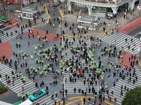 渋谷スクランブル交差点で行われたインスタレーションの様子。緑色の傘を持って100人が行進した