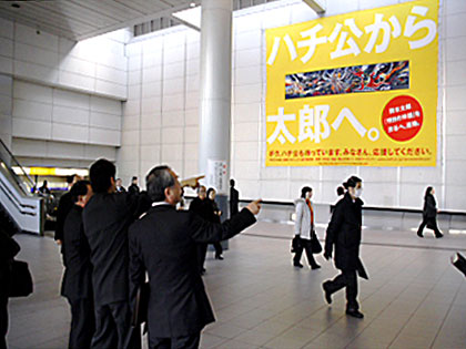 渋谷マークシティ連絡通路に視察に訪れた財団関係者の様子。黄色の懸垂幕がかけられた壁が、提案する招致場所