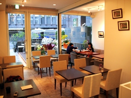 料理で使う食材なども飾る店内。ガラス張りのファサードを挟み、店先にはテラスも広がる
