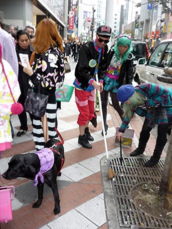 ド派手なオリジナルアイテムに身を包み清掃活動を行うスタッフら。外国人から写真をリクエストされる場面も