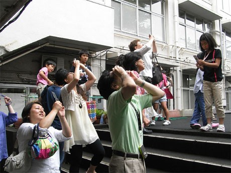 旧代々木高校跡地で行った「日食観望会」。雲の切れ間から見える「日食」を見上げる参加者たち