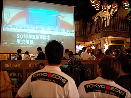 東京落選を伝える大型スクリーンに見入る宮下純一さん（左）と池谷幸雄さん（右）