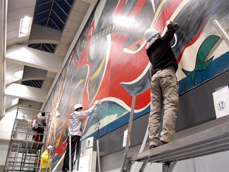 絵画の表面にたまったほこりをはけで払いながら、同時にクリーナーで吸い取る作業が始まった「明日の神話」