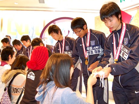 「ナイキフラッグシップストア原宿」に東洋大学陸上部の選手らが登場。来店客に「お守り」を手渡す柏原選手（右）たち