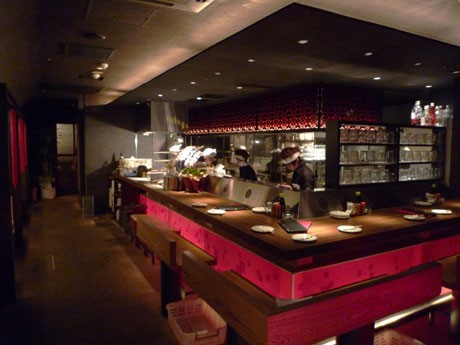 カウンターや壁面などに赤を多用した「地鶏坊主 渋谷本店」の店内