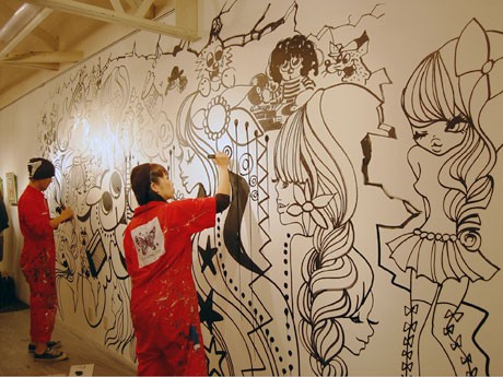 壁面にライブペインティングを行う絵子猫さん（手前）と藤井華丸さん（奥）