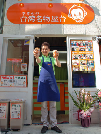 写真は李承芳さん。看板には常連客が描いたという李さんの顔を模したロゴも