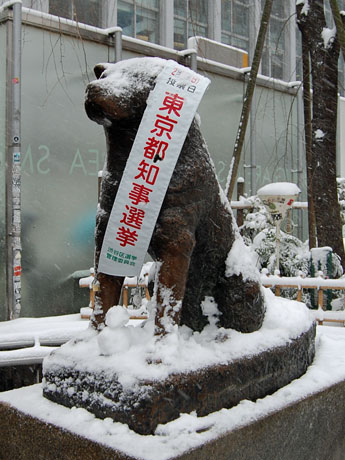 足下に小さな雪だるまが置かれたハチ公像。