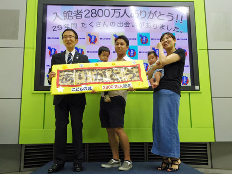 左から藤田興彦理事長と2800万人目の来館者となった美田さん一家