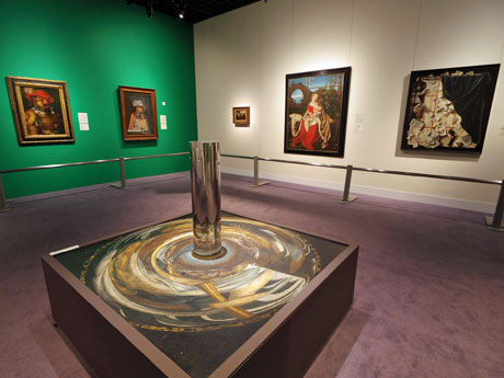 中央に置いた円柱形の鏡の鏡面に渦巻き状の絵を自然な形で映し出す「円柱アナモルフォーズ」の作品（中央）などが並ぶ場内