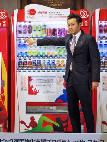 設置するオリジナルラッピングの自販機でコカ・コーラを購入した競泳・北島康介選手