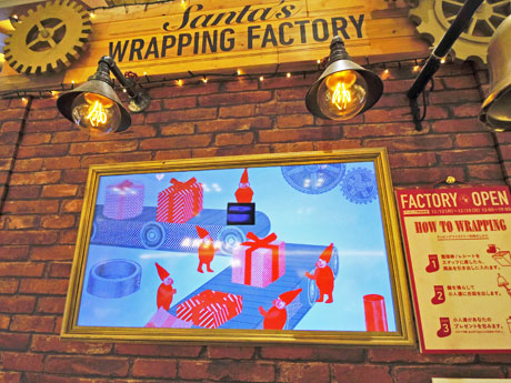 サンタクロースが商品（中央奥の財布）をラッピングしているかのような映像が流れる